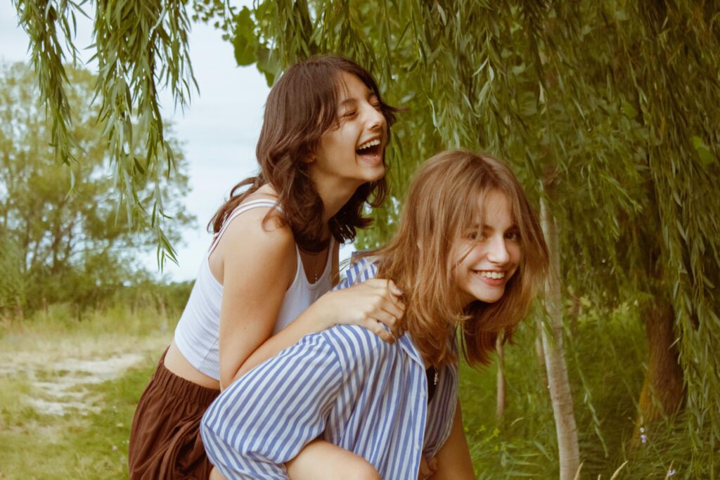 Two young adults share a joyful moment in a lush green forest, evoking happiness and friendship.